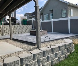 A backyard patio with a stone fire pit, gravel ground cover, and retaining walls.