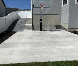 Basketball hoop installed on a concrete patio next to a house.