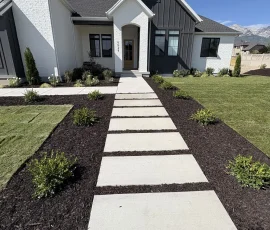 Modern house with a white brick facade and a stone paver walkway leading to the front door.