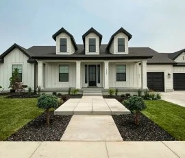 Single-story white farmhouse with black trim, three roof dormers, and a concrete walkway leading to the front porch.